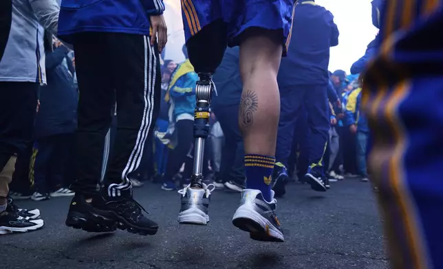 Ignacio Calle jumps with his prosthetic leg while singing Boca Juniors chants before entering the stadium for an Argentina league soccer match in Buenos Aires, Argentina, Saturday, May 9, 2026. (AP Photo/Rodrigo Abd)