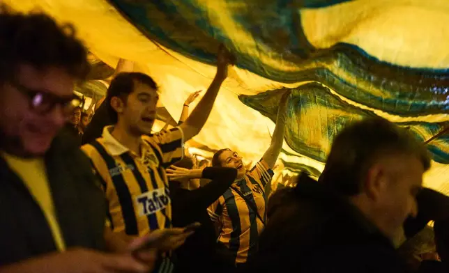 Atlanta fans chant slogans under a flag during an Argentine second-division soccer match against Chacarita Juniors, in Buenos Aires, Argentina, Monday, April 20, 2026. (AP Photo/Rodrigo Abd)