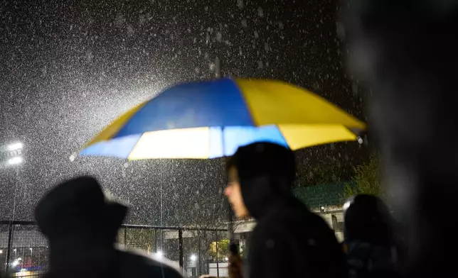 Atlanta fans stand under the rain during an Argentine second-division soccer match against Chacarita Juniors, in Buenos Aires, Argentina, Monday, April 20, 2026. (AP Photo/Rodrigo Abd)