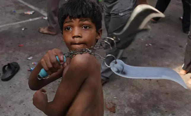 A Shiite Muslim child flagellates himself during a Muharram procession in Ahmedabad, India, Tuesday, June 23, 2026. (AP Photo/Ajit Solanki)