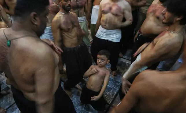 A Shiite Muslim boy beats his chest with others in a ritual during a gathering in the mourning month of Muharram, in Peshawar, Pakistan, late night on Sunday, June 21, 2026. (AP Photo/Muhammad Sajjad)