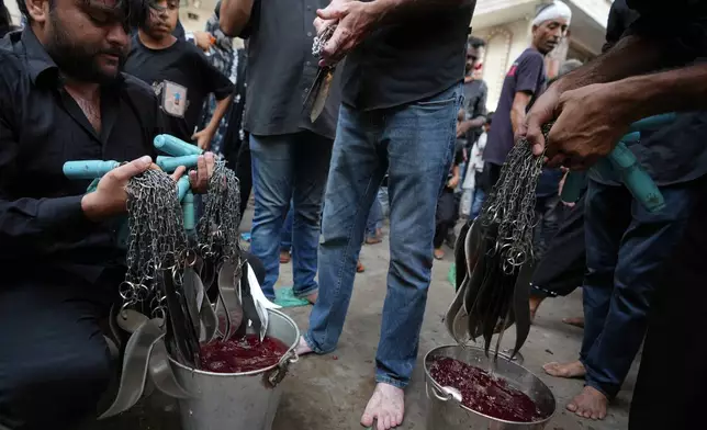 People clean chains, blades and knives after Shiite Muslims flagellate themselves during a Muharram procession in Ahmedabad, India, Tuesday, June 23, 2026. (AP Photo/Ajit Solanki)