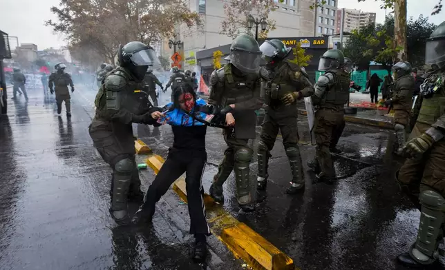 An injured student is detained by police during a protest against the government's proposal to lower the education budget, in Santiago, Chile, Wednesday, June 3, 2026. (AP Photo/Esteban Felix)