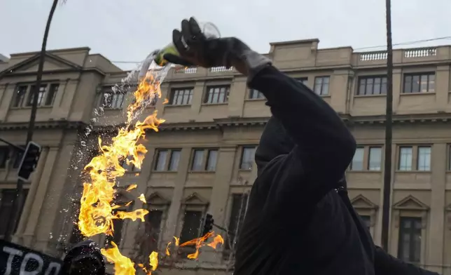A student throws a Molotov cocktail at police during a protest against the government's proposal to lower the education budget, in Santiago, Chile, Wednesday, June 3, 2026. (AP Photo/Esteban Felix)
