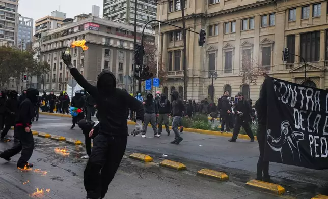 A student throws a Molotov cocktail at police during a protest against the government's proposal to lower the education budget, in Santiago, Chile, Wednesday, June 3, 2026. (AP Photo/Esteban Felix)