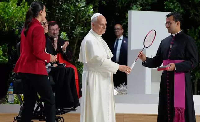 Pope Leo XIV holds a Badminton racket presented to him by Rio 2016 Olympic champion Carolina Marin and by Paralympic athlete Teresa Perales, second from right, during the meeting "Building networks with the world of culture, art, economy and sport" at the Movistar Arena in Madrid, Spain, Sunday, June 7, 2026 (AP Photo/Alessandra Tarantino)
