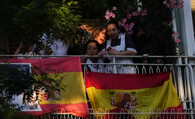 People catch a glimpse from their homes of Pope Leo XIV arriving at Plaza de Lima in Madrid, Saturday, June 6, 2026, for a prayer vigil with young people on the first day of a seven-day apostolic journey to mainland Spain and the Canary Islands. (AP Photo/Alessandra Tarantino)