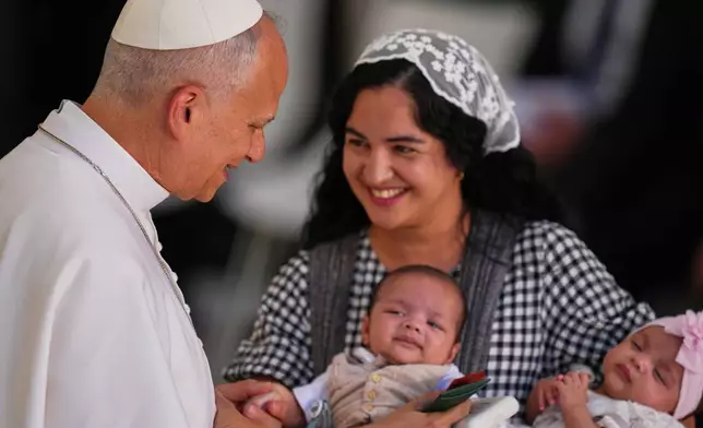 A mother and her two children are greeted by Pope Leo XIV at CEDIA 24 Horas, a comprehensive support center for homeless people, in Madrid, Spain, Saturday, June 6, 2026, on the first day of his seven-day apostolic visit to mainland Spain and the Canary Islands. (AP Photo/Manu Fernandez)