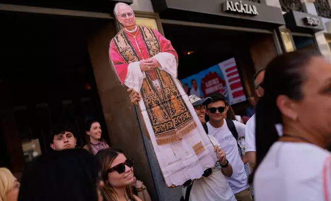 A man holds a portrait of Pope Leo XIV during a Mass marking the Catholic feast of Corpus Christi at Plaza de Cibeles in Madrid, Spain, Sunday, June 7, 2026, on the second day of his seven-day apostolic visit to mainland Spain and the Canary Islands. (AP Photo/Bernat Armangue)