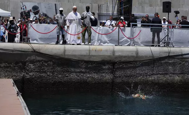 Pope Leo XIV throws a bouquet of flowers into the sea, flanked by migrants, during a meeting with organisations working with migrants in Arguineguin at the Canary Islands, Spain, Thursday, June 11, 2026. (AP Photo/Alessandra Tarantino)