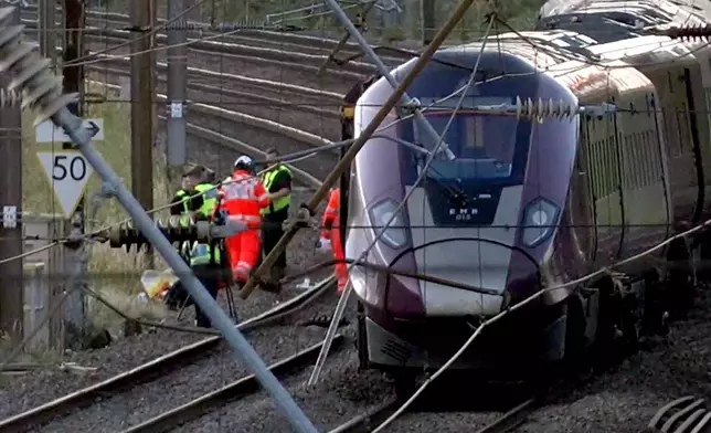 Emergency personnel work on a train on the tracks outside Bedford, England, after a train from Corby to London St. Pancras and another from Nottingham to London St. Pancras, collided on Friday June 19, 2026. (Jamie Lashmar/PA via AP)