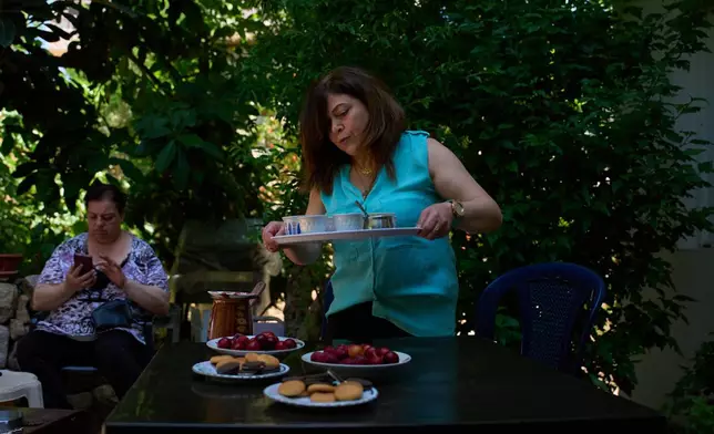 Lolitta Costantine, right, serves coffee as Wadiaa Salloum sits in the garden of her home in the southern town of Jdeidat Marjayoun, Lebanon, Thursday, June 11, 2026. (AP Photo/Hassan Ammar) CORRECTION: City corrected to Jdeidat Marjayoun, instead of Marjayoun
