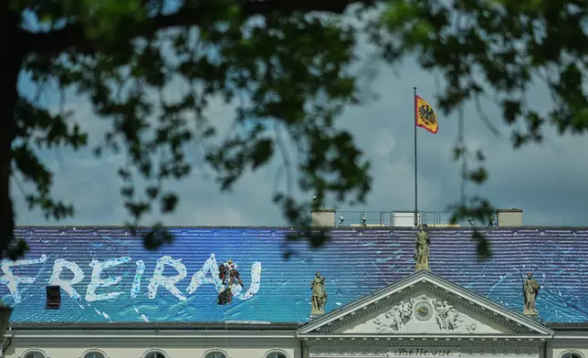 Workers install the artwork "Freiraum Kunst" by Christian Awe on the roof of the German President's residency Bellevue Palace as part of an exhibition of contemporary art at the building in Berlin, Germany, Monday, June 8, 2026. (AP Photo/Markus Schreiber)