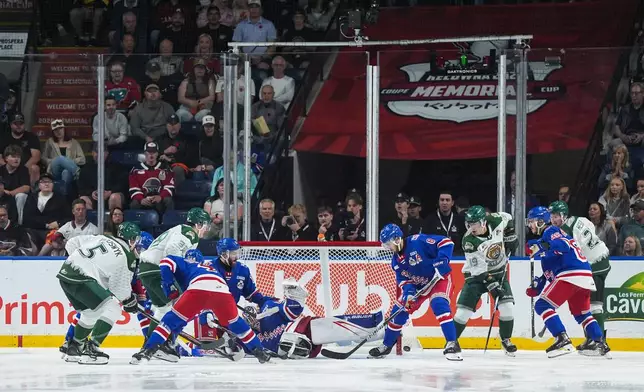 Kitchener Rangers goalie Christian Kirsch (65) sprawls across the net as Carson Campbell (8) collects the puck during the second period of the Memorial Cup final hockey game in Kelowna, British Columbia, Sunday, May 31, 2026. (Darryl Dyck/The Canadian Press via AP)