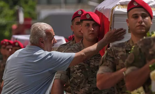 A mourner touches the coffin of the Lebanese army Brig. Gen. Wissam Sabra, who was killed Saturday in south Lebanon along with a captain and a soldier in an Israeli airstrike, during his funeral procession in Beirut, Sunday, June 7, 2026. (AP Photo/Hassan Ammar)