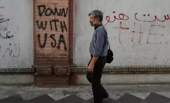 A man walks past anti-U.S. graffiti painted on the wall of the British Embassy in Tehran, Iran, Saturday, June 6, 2026. (AP Photo/Vahid Salemi)