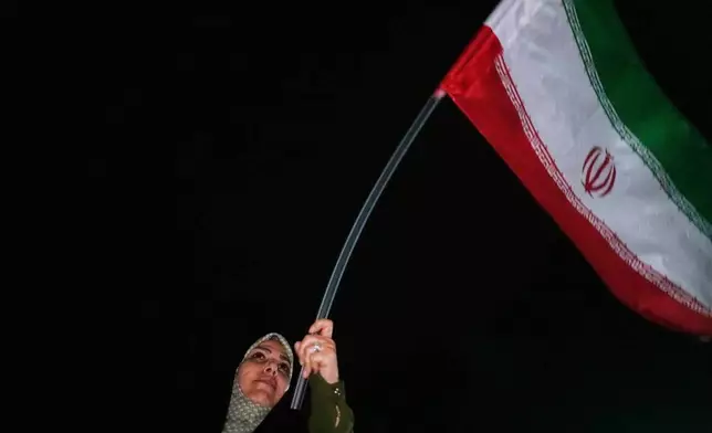 A demonstrator waves an Iranian flag in a pro-government gathering in Tehran, Iran, Sunday, June 7, 2026. (AP Photo/Vahid Salemi)