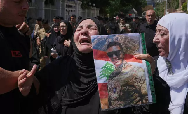 A relative of the Lebanese soldier Hassan Nazzal, who was killed Saturday in south Lebanon along with a brigadier general and a captain in an Israeli airstrike, mourns as she holds his portrait during his funeral procession in Beirut, Sunday, June 7, 2026. (AP Photo/Hassan Ammar)
