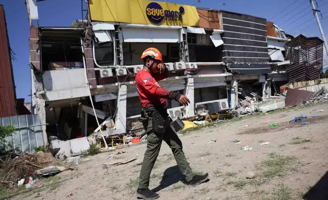A rescuer walks past a damaged building following an earhtquake in General Santos, Philippines Tuesday, June 9, 2026. (AP Photo/Basilio Sepe)