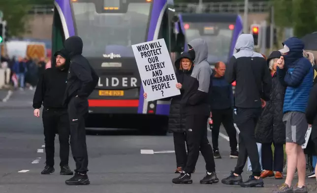 A crowd of protesters gathers in the road following a stabbing incident in North Belfast, Tuesday, June 9, 2026. (AP Photo/Peter Morrison)