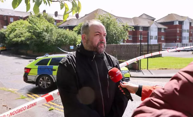 Belfast City Council Councillor Paul McCusker speaking to members of the media near to the scene of a stabbing outside apartments in north Belfast, Tuesday, June 3, 2026. (Liam McBurney/PA via AP)
