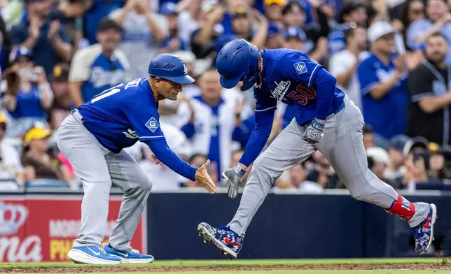Los Angeles Dodgers' Mookie Betts (50) gets a hand from third base coach Dino Ebel, left, after hitting a three-run home run in the sixth inning of a baseball game against the San Diego Padres, Saturday, June 27, 2026, in San Diego. (AP Photo/Tony Ding)