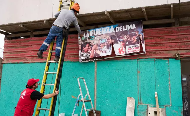 A worker removes a campaign banner of presidential candidate Keiko Fujimori of the Popular Force party placed near a polling station in Lima, Peru, Saturday, June 6, 2026, ahead of Peru's presidential runoff election. (AP Photo/Rodrigo Abd)
