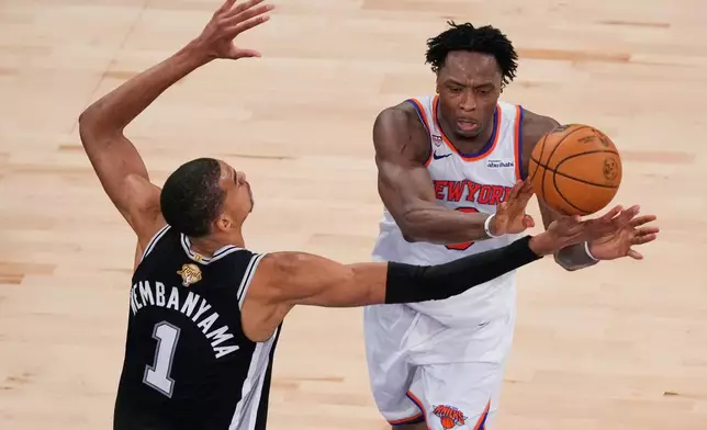 New York Knicks forward Og Anunoby dishes off as San Antonio Spurs forward Victor Wembanyama (1) defends during Game 3 of the NBA Finals basketball series, Monday, June 8, 2026, in New York. (AP Photo/Yuki Iwamura)