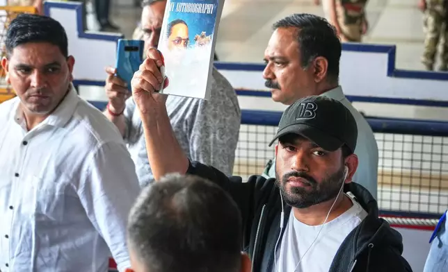 Abhijeet Dipke, center, founder of Cockroach Janta Party shows the autobiography of Bhim Rao Ambedkar as he comes out at Indira Gandhi International airport in New Delhi, India, Saturday, June 6, 2026. (AP Photo/Manish Swarup)