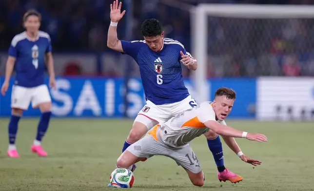 Andri Fannar Baldursson of Iceland falls as he battles for the ball with Wataru Endo of Japan during the friendly soccer international between Japan and Iceland in Tokyo, Sunday, May 31, 2026. (AP Photo/Eugene Hoshiko)