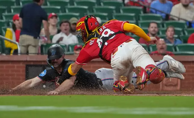 Miami Marlins' Graham Pauley, left, scores ahead of the tag from St. Louis Cardinals catcher Iván Herrera during the eighth inning of a baseball game Friday, June 26, 2026, in St. Louis. (AP Photo/Jeff Roberson)