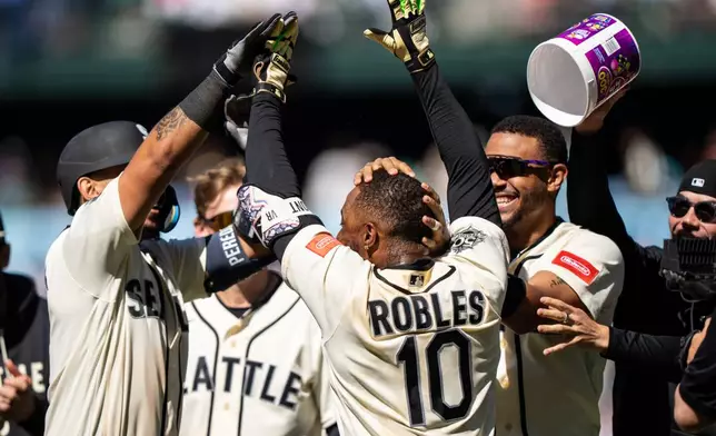 From left to right, Seattle Mariners' Jhonny Pereda, Colt Emerson, Victor Robles and Julio Rodriguez celebrate after a baseball game against the Arizona Diamondbacks, Sunday, May 31, 2026, in Seattle. (AP Photo/Stephen Brashear)