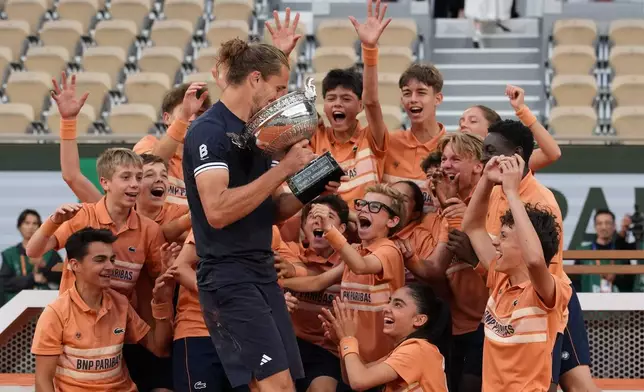Ballboys and ballgirls react as Alexander Zverev of Germany celebrates with the trophy after winning the men's final match against Flavio Cobolli of Italy at the French Open tennis tournament in Paris, Sunday, June 7, 2026. (AP Photo/Christophe Ena)
