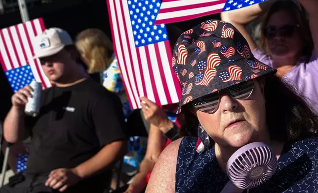 A person cools down with a portable fan ahead of President Donald Trump's speech at the opening of the Great American State Fair on the National Mall, Wednesday, June 24, 2026, in Washington. (AP Photo/Julia Demaree Nikhinson)