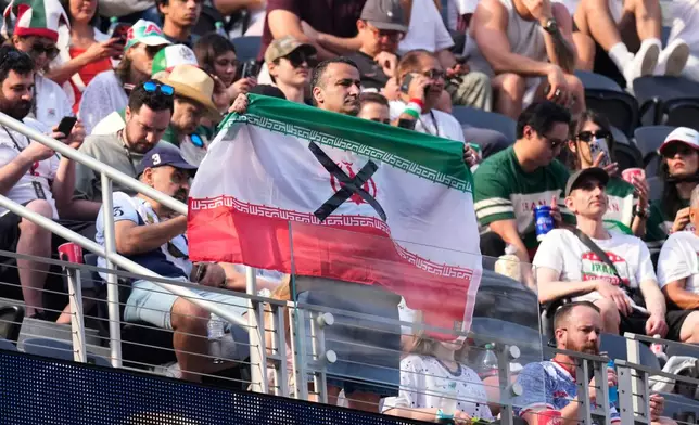 An attendees holds an Iranian flag with an "X" on it before the World Cup Group G soccer match between Iran and New Zealand in Inglewood, Calif., near Los Angeles, Monday, June 15, 2026. (AP Photo/Mark J. Terrill)