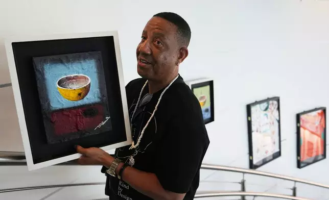 Alfonso D. Brooks, founder of AfriKin, holds a painting of a calabash by artist Bamazi Talle at an exhibition, "Art and the Beautiful Game: Africa on the World Stage," on May 30, 2026, in North Miami, Fla. (AP Photo/Lynne Sladky)