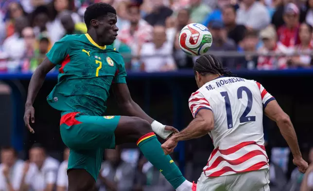 United States defender Miles Robinson (12) heads the ball away from Senegal forward Assane Diao (7) during the second half of an international friendly soccer match Sunday, May 31, 2026, in Charlotte, N.C. (AP Photo/Scott Kinser)