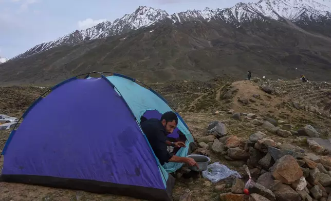A spectator washes a dish after preparing tea in his tent during the three-day annual Shandur Polo Festival in Shandur Pass, in the Ghizer district of Gilgit-Baltistan, northern Pakistan, Friday, June 12, 2026. (AP Photo/Zubair Abbasi)