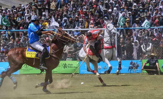 Players of Chitral region team, in red, and Gilgit-Baltistan region team, in blue, battle for the ball during the final match of the three-day annual Shandur Polo Festival in Shandur Pass, in the Ghizer district of Gilgit-Baltistan, northern Pakistan, Saturday, June 13, 2026. (AP Photo/Zubair Abbasi)