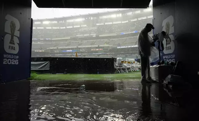 A photographer shelters from the rain as play is suspended during the World Cup Group I soccer match between France and Iraq in Philadelphia, Monday, June 22, 2026. (AP Photo/Petr David Josek)