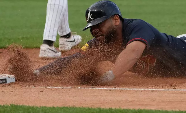 Atlanta Braves' Dominic Smith dives into first base safely against the Chicago White Sox during the third inning in a baseball game Wednesday, June 10, 2026, in Chicago. (AP Photo/David Banks)