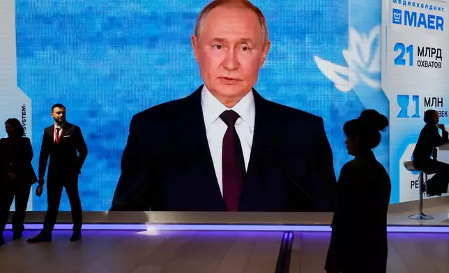 People walk past a screen with an image of Russian President Vladimir Putin at an exhibition at the St. Petersburg International Economic Forum in St.Petersburg, Russia, on Thursday, June 4, 2026. (Anatoly Maltsev/Pool Photo via AP)