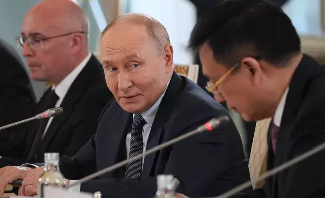 Russian President Vladimir Putin, center, looks at President of Xinhua News Agency Fu Hua, right, while speaking to representatives of international news agencies as General Director of the Russian news agency TASS, Andrey Kondrashov, left, sits near on the sidelines of the St. Petersburg International Economic Forum at the Constantine Palace in St. Petersburg, Russia, on Thursday, June 4, 2026. (AP Photo/Dmitri Lovetsky, Pool)
