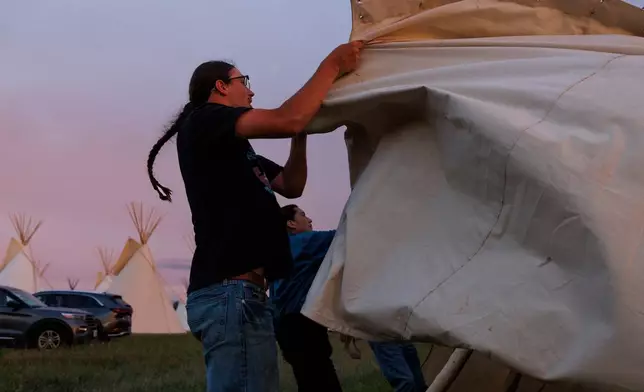 Dawson Richards helps his father set up a tepee during festivities commemorating the 150th anniversary of the Battle of the Little Bighorn, Wednesday, June 24, 2026, in Crow Agency, Mont. (AP Photo/Tailyr Irvine)