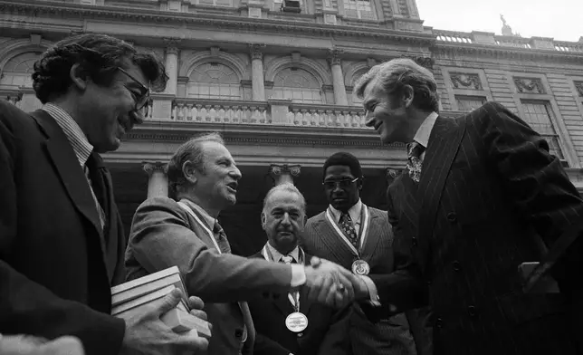 FILE - New York Mayor John Lindsay, right, congratulates Red Holzman, coach of the New York Knicks, after presenting the city's diamond jubilee medals to Holzman and other members of the Knicks team on the steps of City Hall on May 15, 1973. Shown with the mayor are Irving Felt, board chairman of Madison Square Garden, second from left, and Willis Reed, team captain, next to Lindsay. (AP Photo/Anthony Camerano, File)