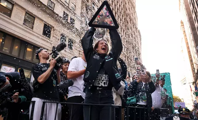 FILE - New York Liberty guard Sabrina Ionescu holds up the WNBA basketball championship trophy while riding down Broadway during a parade celebrating the team's season championship, Oct. 24, 2024, in New York. (AP Photo/Yuki Iwamura, File)