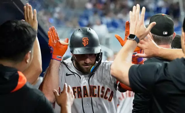 San Francisco Giants' Casey Schmitt is congratulated in the dugout after scoring on solo home run during the fourth inning of a baseball game against the Miami Marlins, Saturday, June 20, 2026, in Miami. (AP Photo/Lynne Sladky)