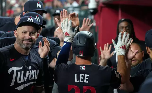Minnesota Twins' Brooks Lee, center, gets high fives from teammates after scoring a run against the Arizona Diamondbacks during the fourth inning of a baseball game Saturday, June 20, 2026, in Phoenix. (AP Photo/Darryl Webb)