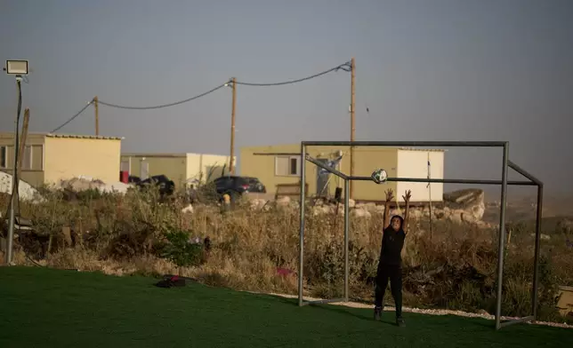 Backdropped by caravans from the Israeli settlement of Carmel, a Palestinian boy jumps for a ball while playing goalkeeper at a small soccer pitch in the West Bank Bedouin village of Umm al-Khair, Tuesday, May 12, 2026. (AP Photo/Leo Correa)