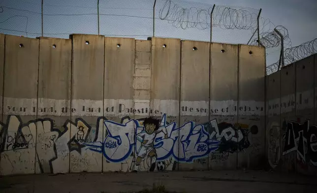 A mural of a youth running with a soccer ball covers Israel's separation wall in the West Bank town of Al-Ram, Monday, May 11, 2026. (AP Photo/Leo Correa)